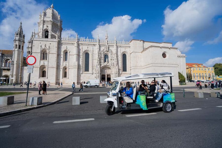 Lisbon: Belem Sightseeing Tour by Tuk Tuk with local guide - Leaving central Lisbon under the 25 de Abril Bridge